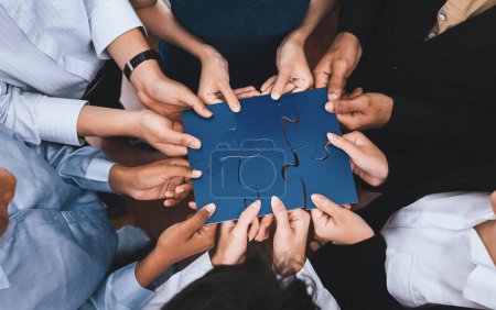 Photo for Diverse corporate officer workers collaborate in office, connecting puzzle pieces to represent partnership and teamwork. Unity and synergy in business concept by merging jigsaw puzzle. Concord - Royalty Free Image
