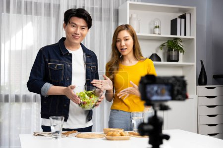 Photo for Cooking show on live streaming with two chef influencers teaching mixed salad with dressing for easy special recording on video camera. Ingredients placing bread bun wholegrain side dish. Infobahn. - Royalty Free Image