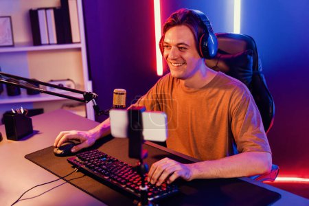 Photo for Host channel of gaming smart streamer playing online game, wearing headphone with viewers live steaming on media social online by smartphone talking with team player at neon lighting room. Pecuniary. - Royalty Free Image