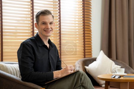 Photo for Portrait of happy and smiling male psychologist portrait sitting on arm chair in psychiatrist office or therapy room. Friendly and professional mental healthcare counselor and therapist. Unveiling - Royalty Free Image
