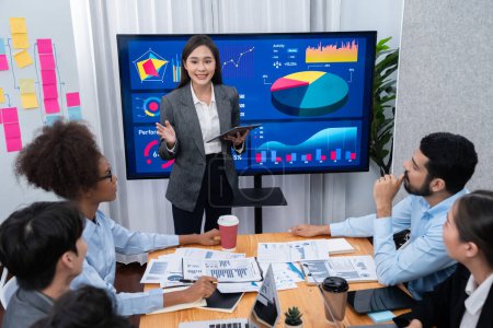Téléchargez les photos : Jeune femme d'affaires asiatique présentant le tableau de bord d'analyse de données sur l'écran de télévision dans la réunion moderne. Présentation d'affaires avec un groupe de gens d'affaires en salle de conférence. Concord - en image libre de droit