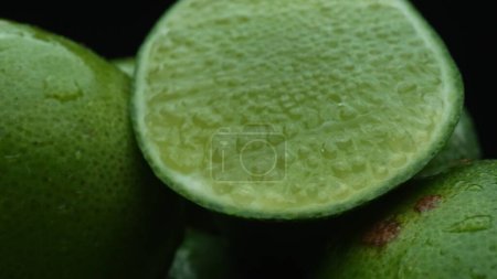 Les tranches de chaux sont soigneusement disposées en tas, sur un fond noir. Chaque tranche de citron vert est capturée dans des détails époustouflants, sa teinte verte vibrante et sa texture attrayante. Ferme là. Comestible.