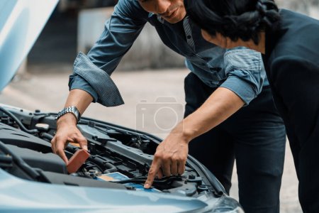 Téléchargez les photos : L'homme aide la femme à résoudre le problème de la voiture. Il fait sauter le capot pour réparer la partie endommagée. uds - en image libre de droit