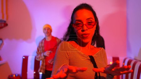 Multicultural friend dancing together and moving along hiphop music while standing at restaurant or cafe with pink neon light. Professional street dancer group perform energetic movement. Regalement.