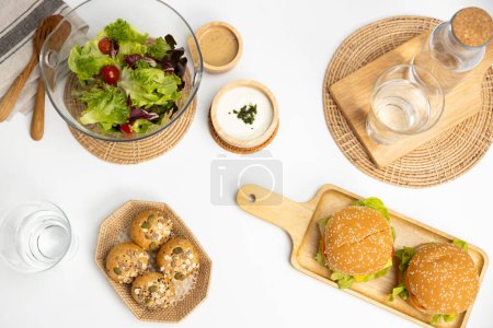 Photo for Top view of tasty food in double meat hamburger, salad, wholegrain bun on meal cooked by homemade serving on white table background. Preparing special dish menu lists restaurant or cafe. Infobahn. - Royalty Free Image