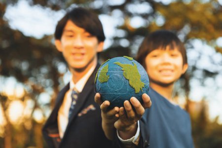 Photo for Focus Earth with blurred asian boy and businessman holding globe together as Earth day concept as corporate social responsible to make greener environmental for sustainable future generation. Gyre - Royalty Free Image