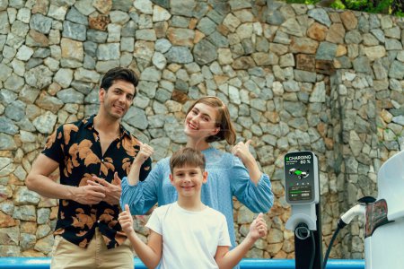 Photo for Family road trip vacation with electric vehicle, lovely family recharge EV car with green and clean energy. Stone seawall background and eco friendly car travel for sustainable environment. Perpetual - Royalty Free Image
