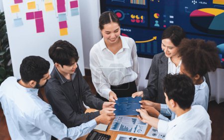 Photo for Corporate officer worker collaborate in office, connecting puzzle pieces with report paper on table as partnership and teamwork. Unity and synergy in business concept by merging jigsaw puzzle. Concord - Royalty Free Image