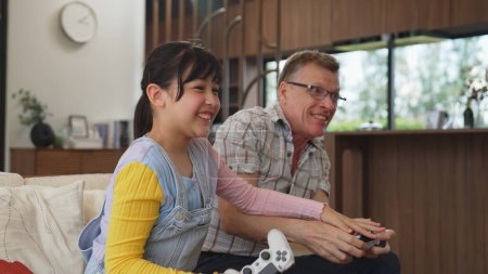 Grandfather and granddaughter together play console game, entertainment media. Old senior use technology communicate with new generation kid cross generation gap strengthen family bond. Divergence.