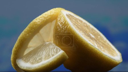 A slice of fresh lemon, bright yellow and vibrantly citric, lies exposed. The flesh, glistening with refreshing juice, reveals its segmented interior. The essence of citrus vibrancy. Comestible.