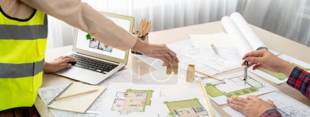 Professional engineer and architect collaborate on eco house project at meeting table with green design blueprint and architectural equipment at modern office. Focus on hand. Close up. Delineation.