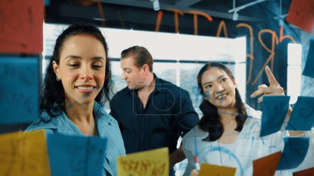 Photo for Portrait of professional diverse business team brainstorming marketing idea on colorful sticky notes stuck on glass board. Hispanic project manager write business strategy on note. Manipulator. - Royalty Free Image