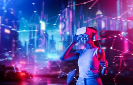 Photo for Female standing in cyberpunk style building in meta wear VR headset connecting metaverse, future cyberspace community technology. Woman touching goggle looking far virtual construction. Hallucination. - Royalty Free Image