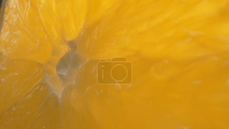 Foto de La macrofotografía de una naranja en rodajas con vibrante color naranja y visible en la jugosa carne de los cítricos. La pulpa de la naranja parece regordeta, insinuando su jugosidad. Comestible. - Imagen libre de derechos