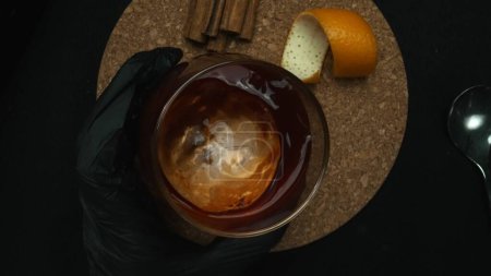 Vue de dessus d'un cocktail Negroni prend le devant de la scène, orné d'une tranche d'orange vibrante sur un fond noir élégant. Chaque plan rapproché méticuleux capture un cocktail. Macrographie. Comestible.