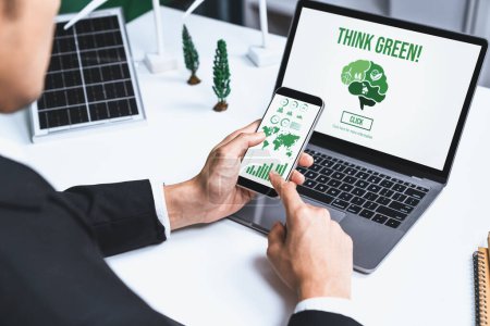Businessman working in office developing plan or project on eco-friendly alternative energy with solar cell technology display on computer screen for greener environment as apart of CSR effort. Gyre