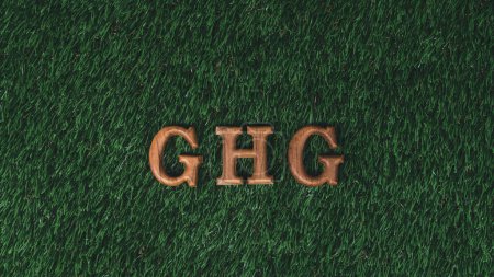Arranged wooden alphabet text in GHG on biophilic green grass background as eco symbol for encouraging message for reduction of greenhouse gases emission campaign and environmental awareness. Gyre