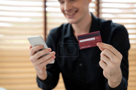 Photo for Young man using laptop with credit card for internet banking, online shopping E commerce by online payment gateway at home office. Modern and convenience online purchasing with debit card. Unveiling - Royalty Free Image