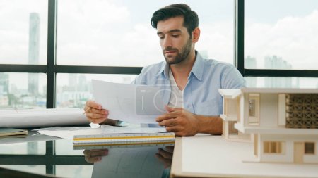Photo for Skilled smart architect engineer writing house construction on blueprint at table with house model, architectural equipment, Interior designer draw, draft, plan building design at office. Disputation - Royalty Free Image