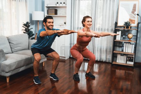Couple athlétique et sportif faisant squat ensemble pendant la séance d'entraînement du corps à la maison séance d'exercice pour forme physique et mode de vie sportif sain à la maison. Gaiety exercice à domicile concept de formation d'entraînement.