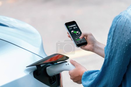 Téléchargez les photos : Branchez le chargeur EV main dans le véhicule électrique pour recharger la voiture EV, affichage de l'état de la batterie sur l'application smartphone EV. Énergie propre et durable future pour les transports. Perpétuel - en image libre de droit