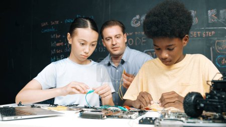 Smart Mentor lehren Hauptplatinenkonstruktion, während diverse Teenager Lernsystem. Der Lehrer erklärt die Struktur des Motherboards, während der Schüler lernt, elektronische Geräte zu benutzen. Erbauung.