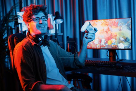 Host channel of young gaming streamer looking at camera, holding joystick to present fighting Moba battle arena game multiplayer team against on screen background at neon digital light room. Gusher.