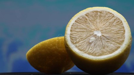 A slice of fresh lemon, bright yellow and vibrantly citric, lies exposed. The flesh, glistening with refreshing juice, reveals its segmented interior. The essence of citrus vibrancy. Comestible.