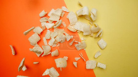 Photo for Top down view of snack flying in the air from explosion and falling or dropping at separated yellow and orange background. Aerial view of snack flying at yellow backdrop. Slow motion. Snack. Pabulum. - Royalty Free Image