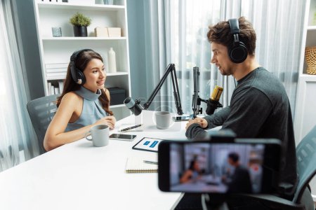 Focus on host channel broadcaster making advice problem in live streaming with listeners surrounded sets of live streaming on talking show radio recorded blurry smartphone at modern studio. Postulate.