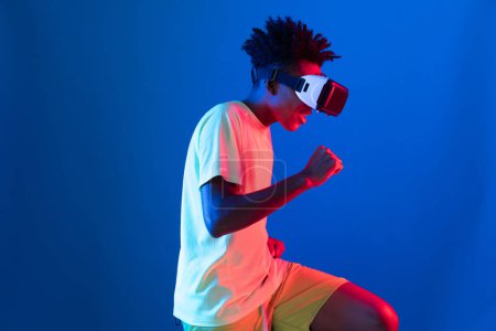 Téléchargez les photos : Jeune coureur sportif afro-américain portant un exercice de course VR courir compétition de course sur le mur néon rose bleu reliant la technologie futuriste réalité virtuelle au monde métaverse. Contrivance. - en image libre de droit