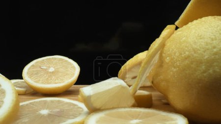 Close up of lemon slices are meticulously arranged against a rustic basket backdrop on a deep black surface. Each slice, bathed in soft light against the dark background, Macrography. Comestible.